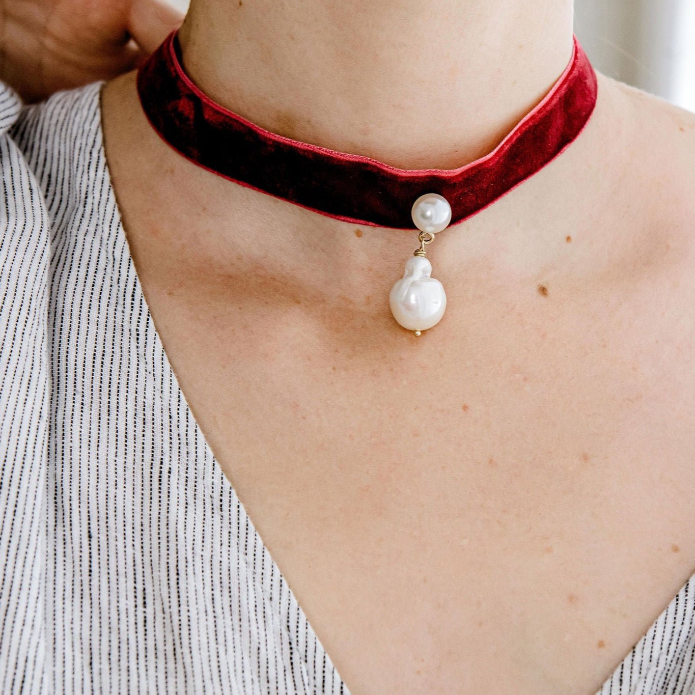 Velvet pearl choker with freshwater pearls and gold detail, tied in a bow for an adjustable fit