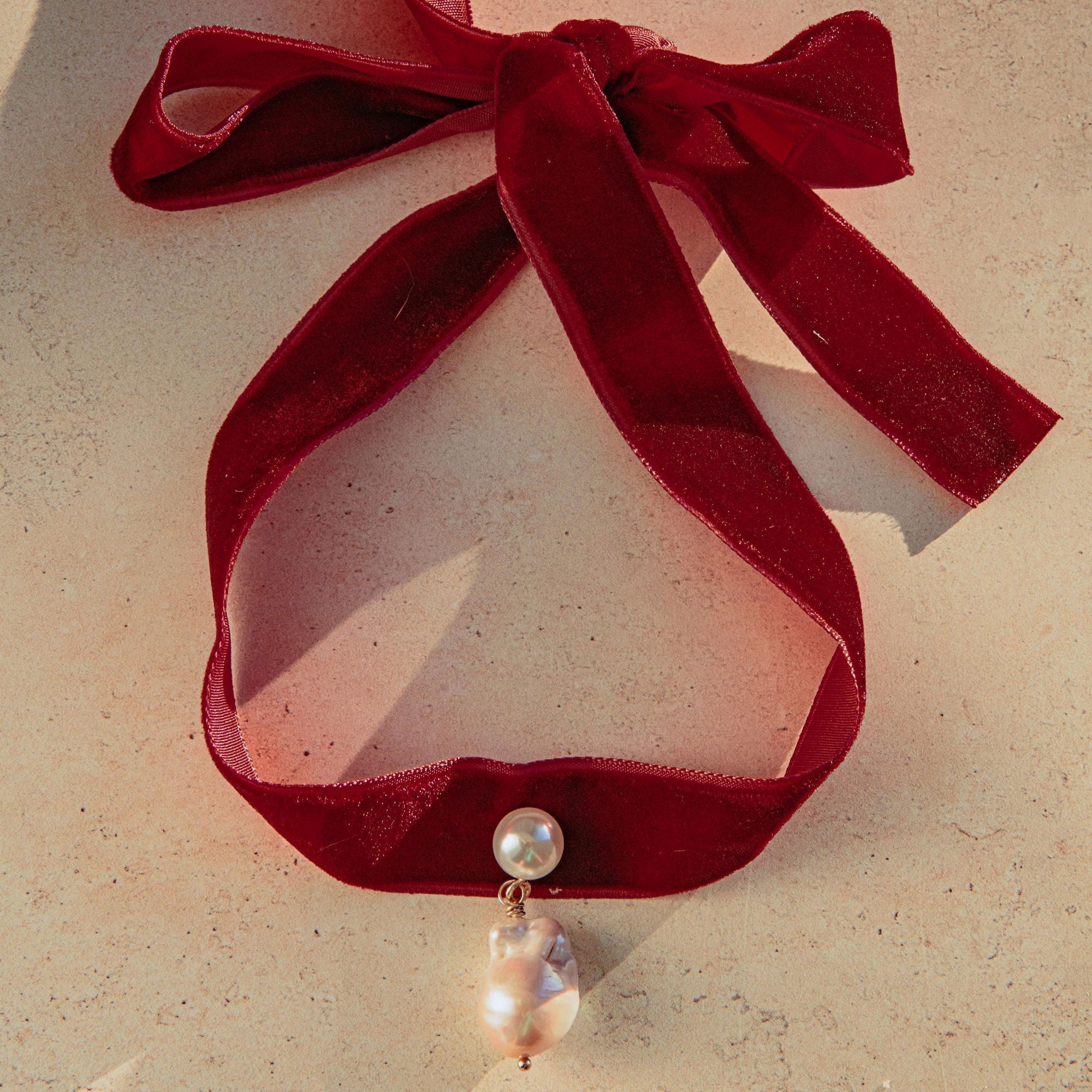 Velvet pearl choker with freshwater pearls and gold detail, tied in a bow for an adjustable fit