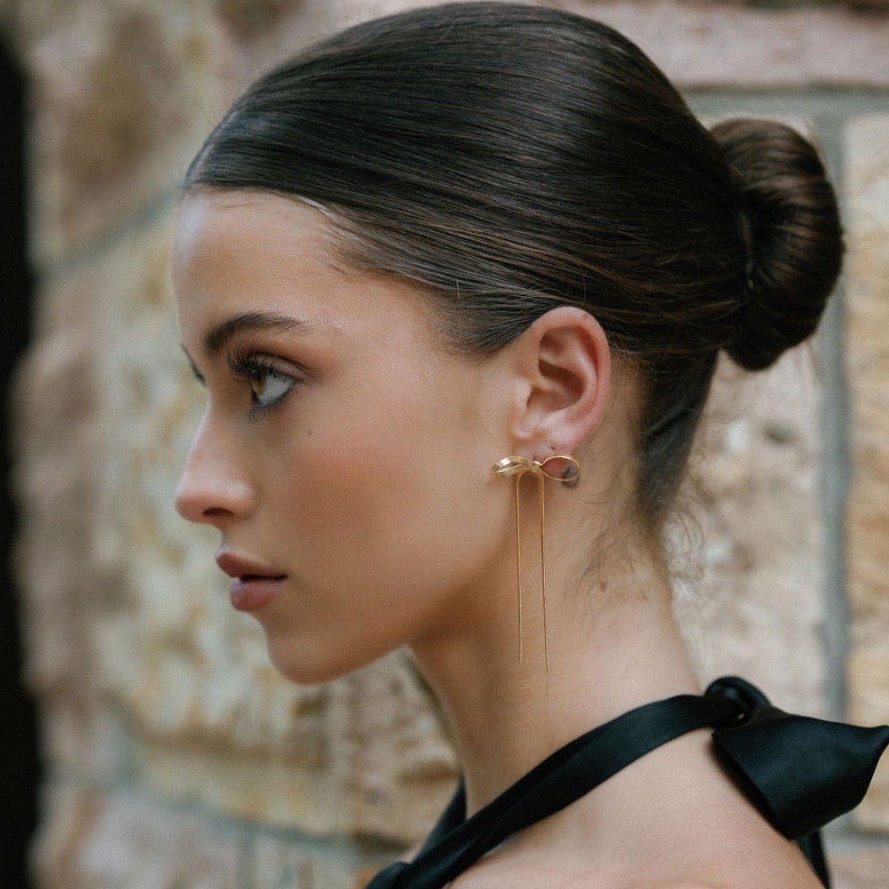 statement gold bow earrings with drop chain design