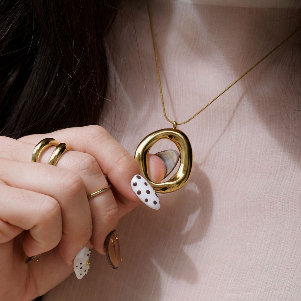 Kyra gold pendant necklace with a polished organic open-centre design and the Cove gold ring.