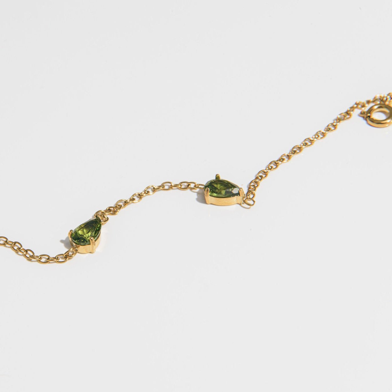 gold bracelet with green teardrop-cut stones