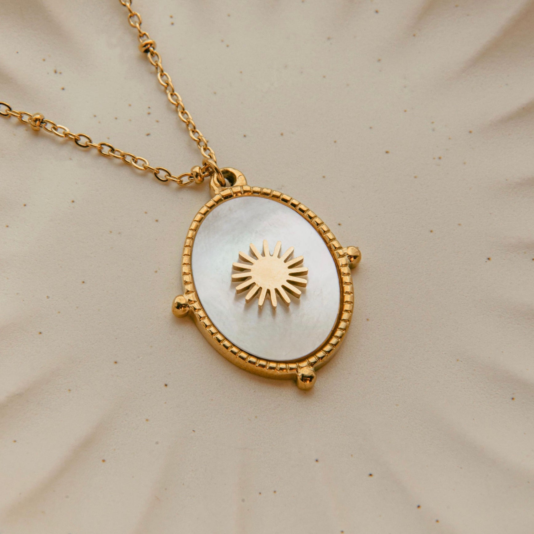 Gold sunburst pendant necklace with mother of pearl inlay and waterproof beaded frame
