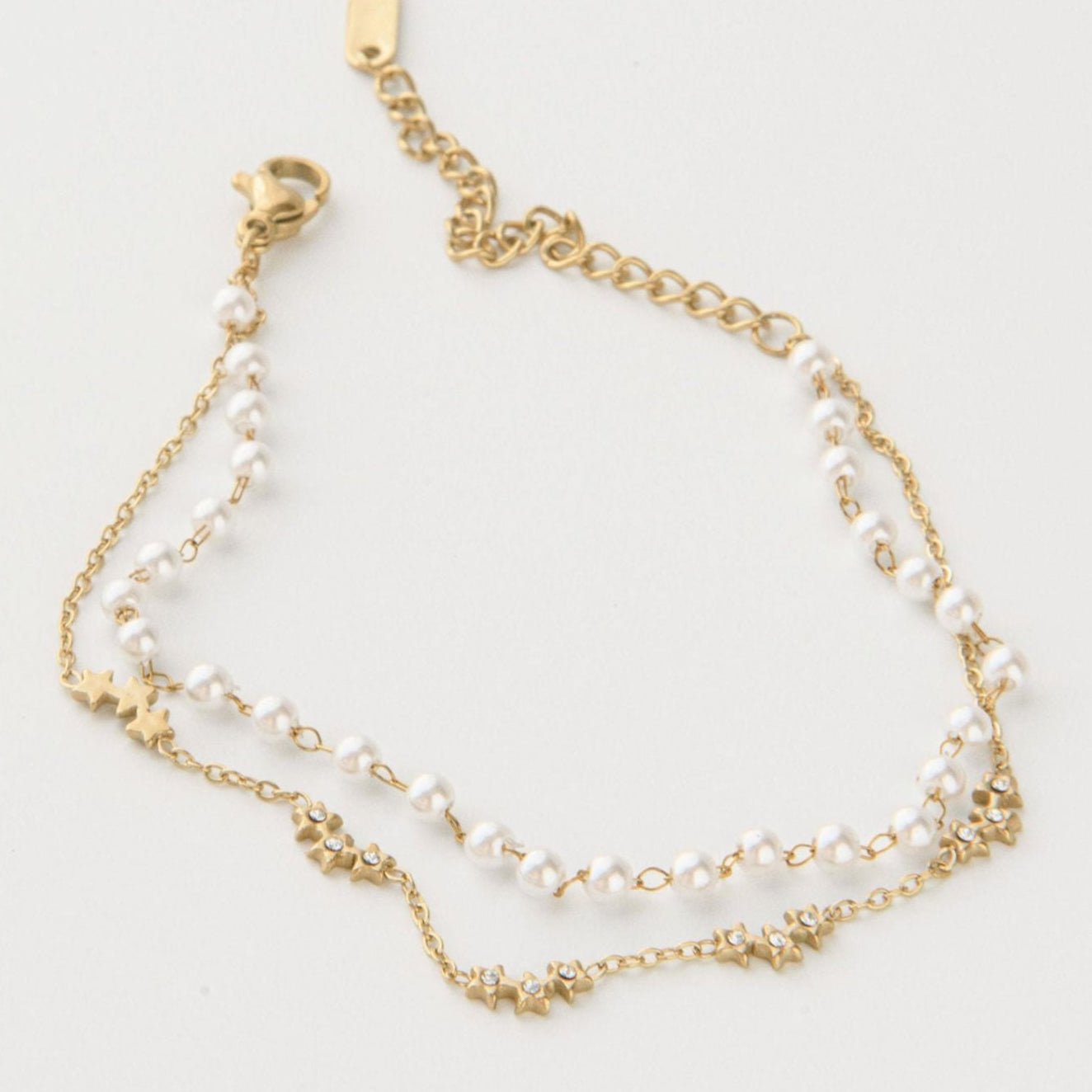 Gold pearl bracelet with freshwater pearls, gold star charms, and Cubic Zirconia on a waterproof double chain