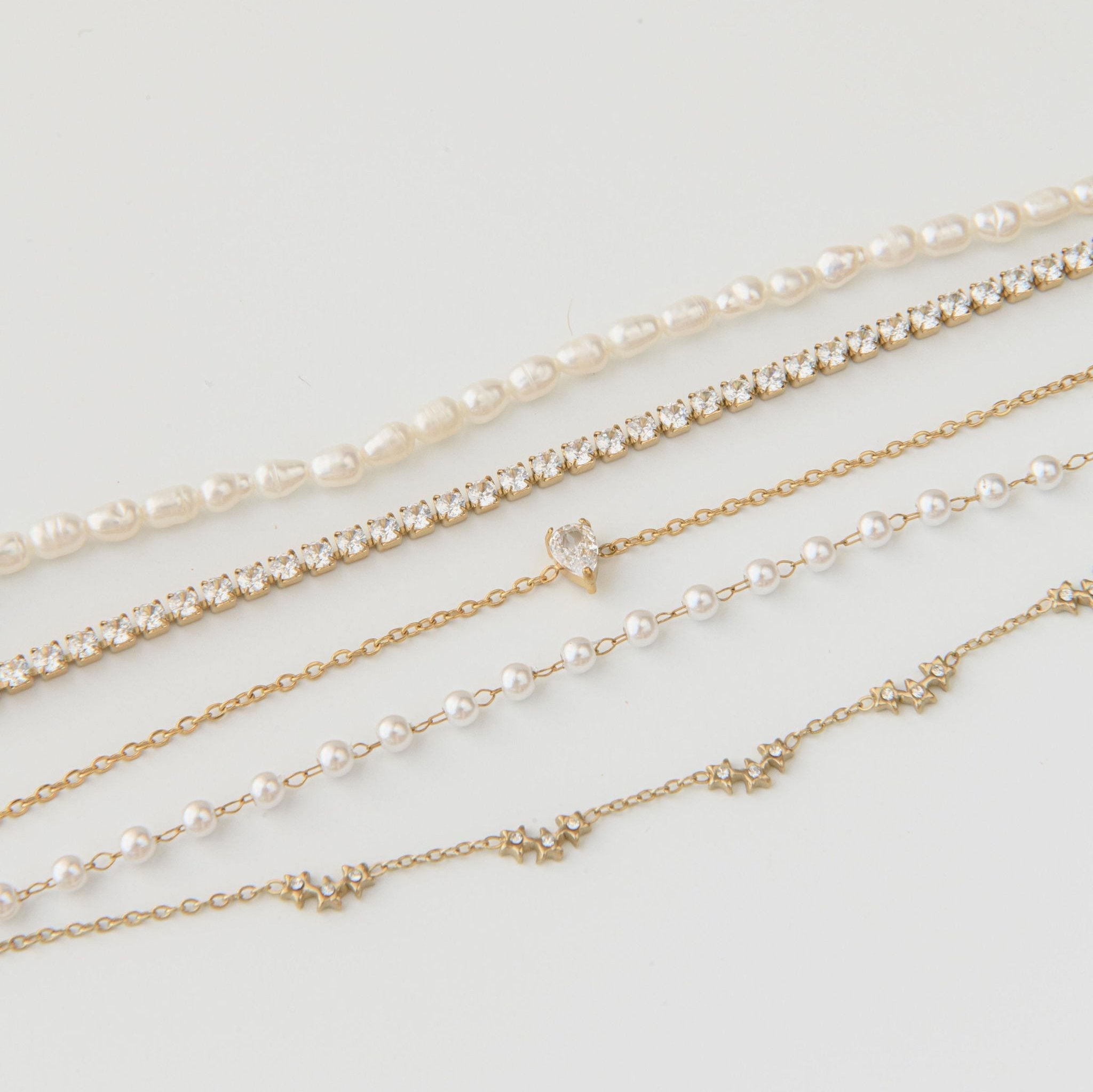 Gold pearl bracelet with freshwater pearls, gold star charms, and Cubic Zirconia on a waterproof double chain