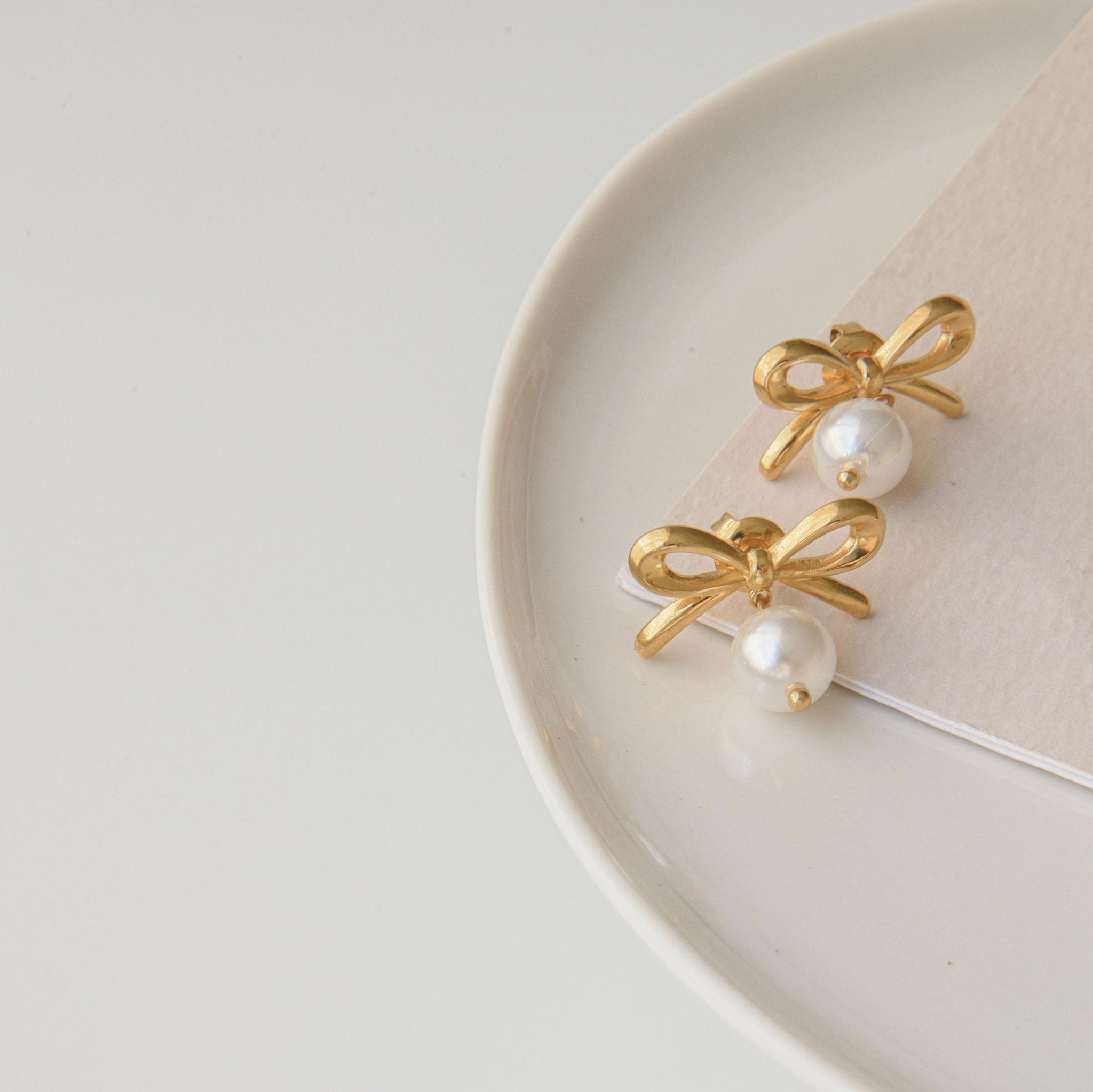 Gold pearl earrings with freshwater pearl drops and waterproof bow design