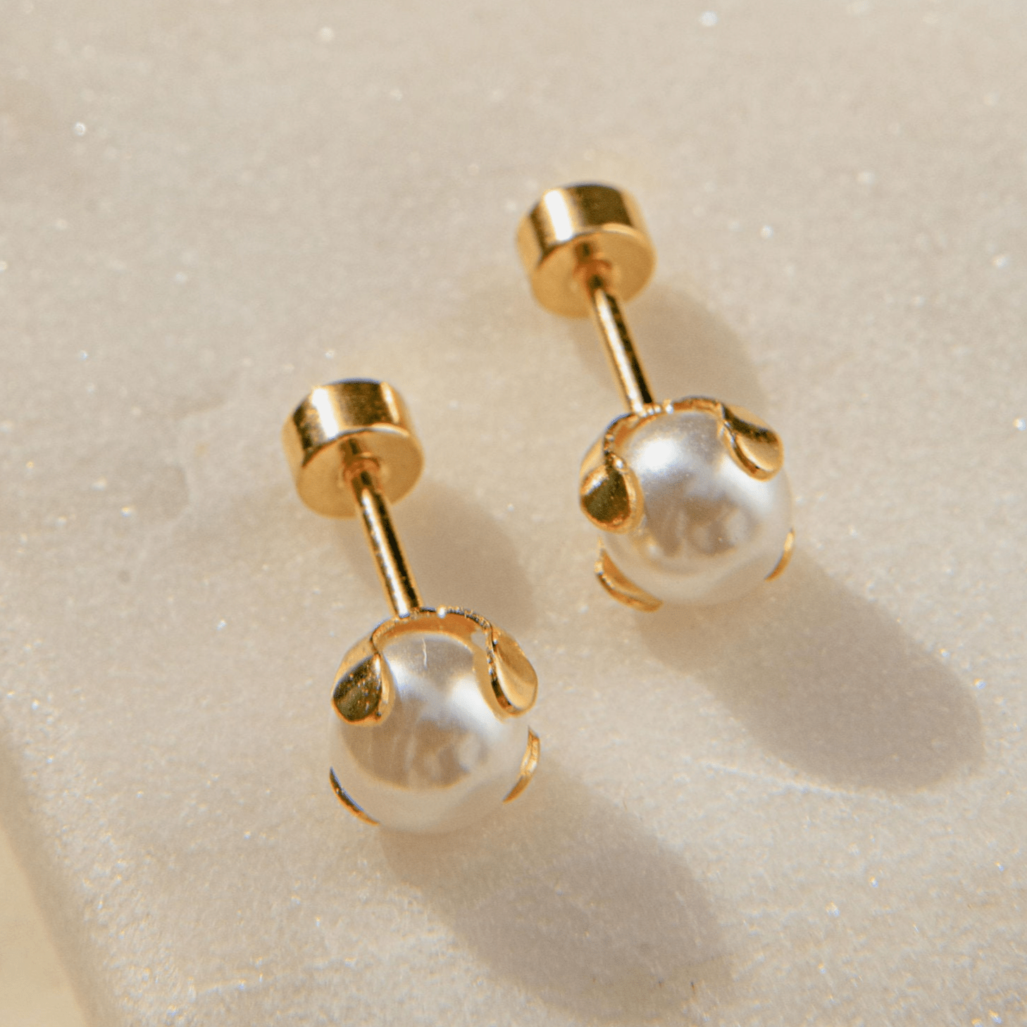 Delicate gold pearl earrings with four-claw setting and freshwater pearls in a ballback stud design