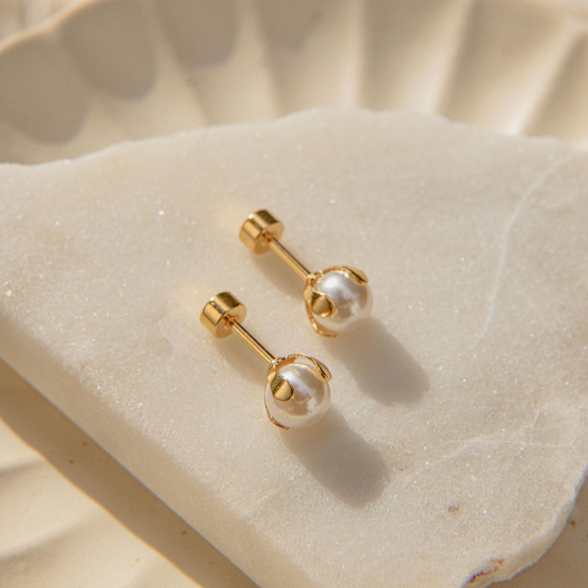 Delicate gold pearl earrings with four-claw setting and freshwater pearls in a ballback stud design