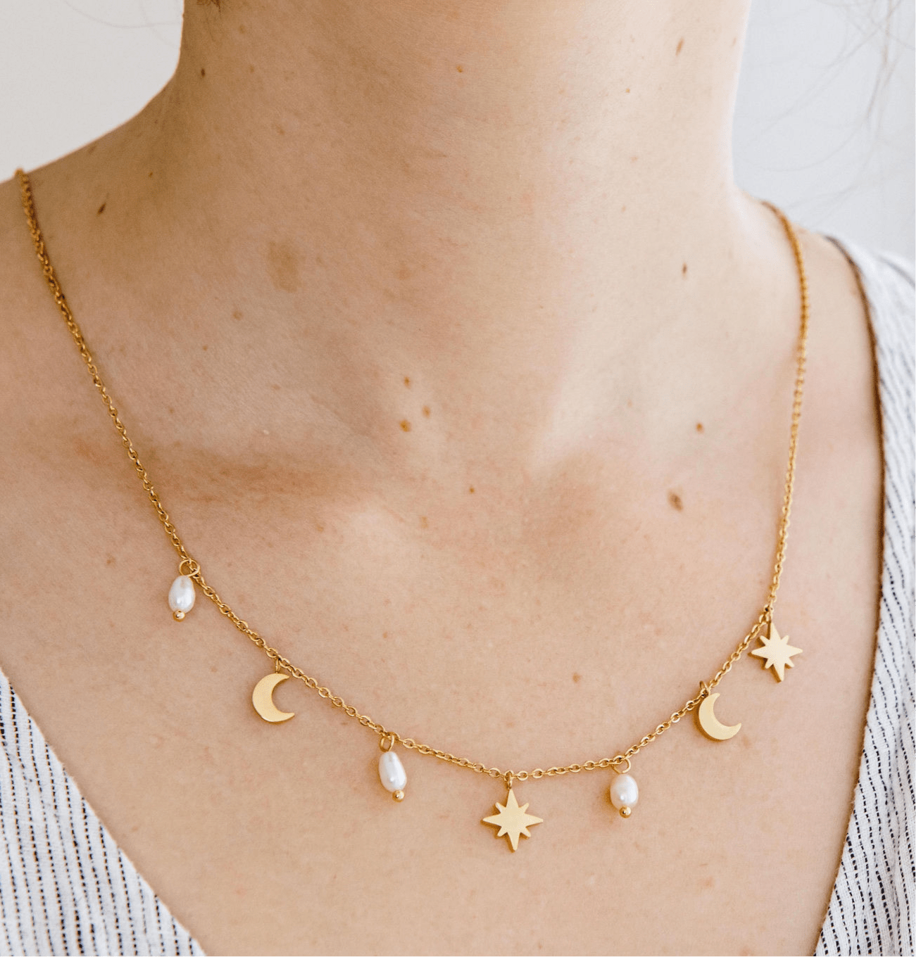 Gold pearl necklace with freshwater pearls and celestial star and moon charms on a waterproof gold chain